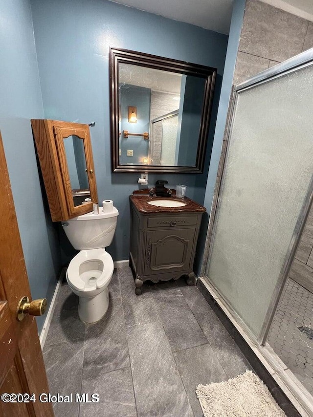 bathroom with tile patterned floors, vanity, toilet, and a shower with shower door