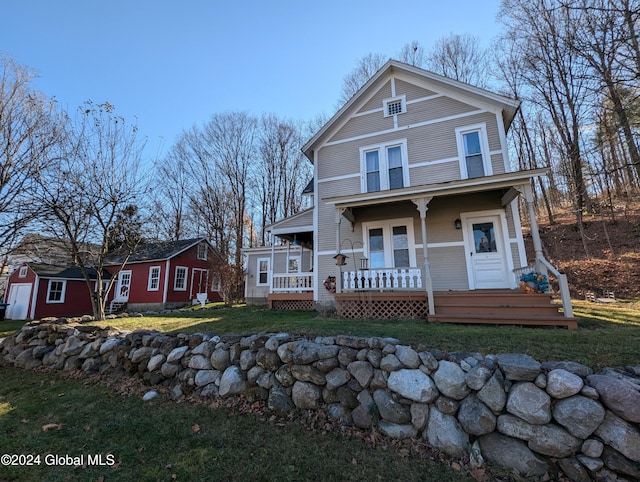 view of front of home featuring a porch, a storage shed, and a front lawn