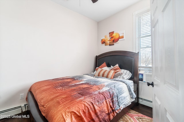 bedroom with a baseboard radiator, dark hardwood / wood-style flooring, and multiple windows