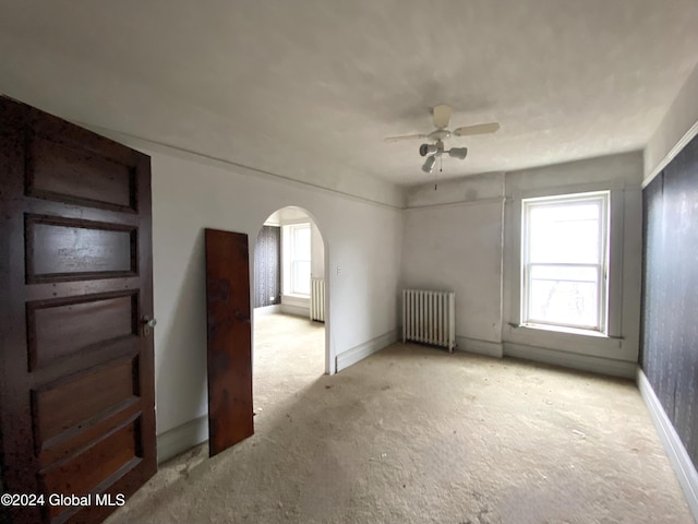 carpeted spare room featuring ceiling fan and radiator heating unit