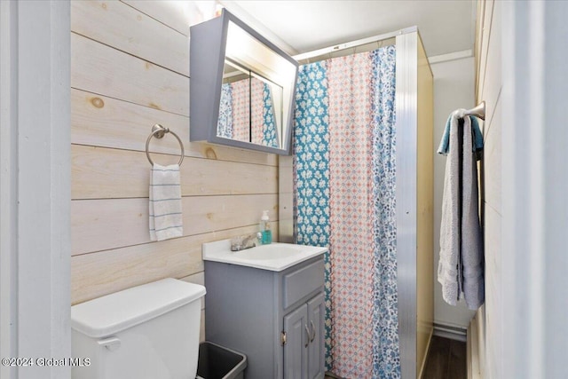 bathroom featuring toilet, vanity, wooden walls, and a shower with curtain