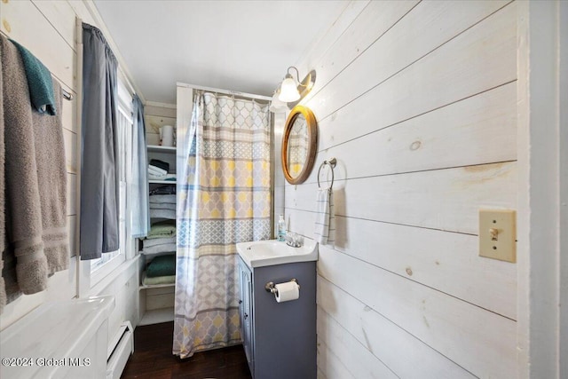 bathroom with vanity, hardwood / wood-style floors, a baseboard heating unit, and wood walls