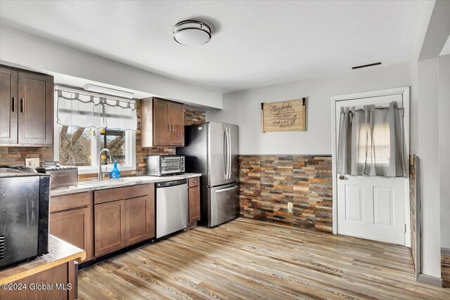 kitchen featuring sink, light wood-type flooring, stainless steel appliances, and tasteful backsplash