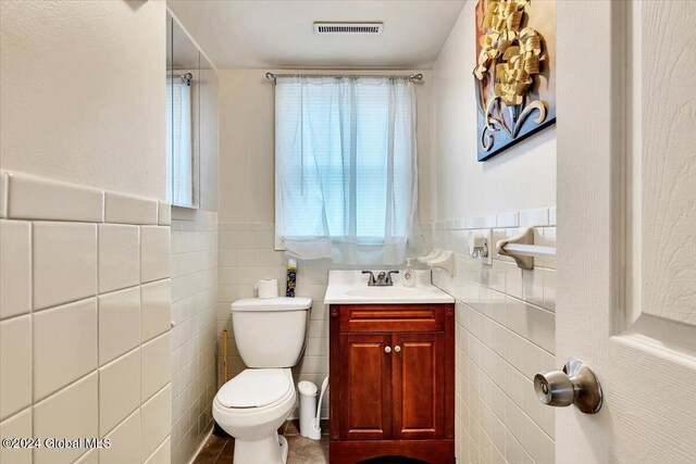 bathroom featuring vanity, toilet, and tile walls