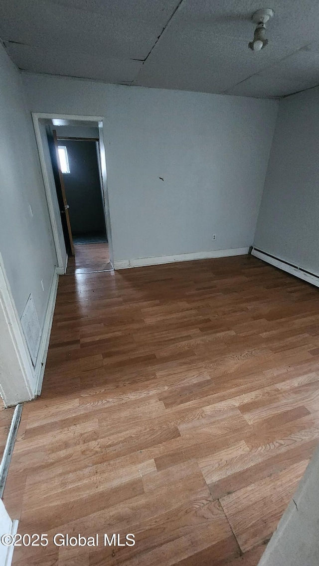 unfurnished room featuring wood-type flooring and baseboard heating