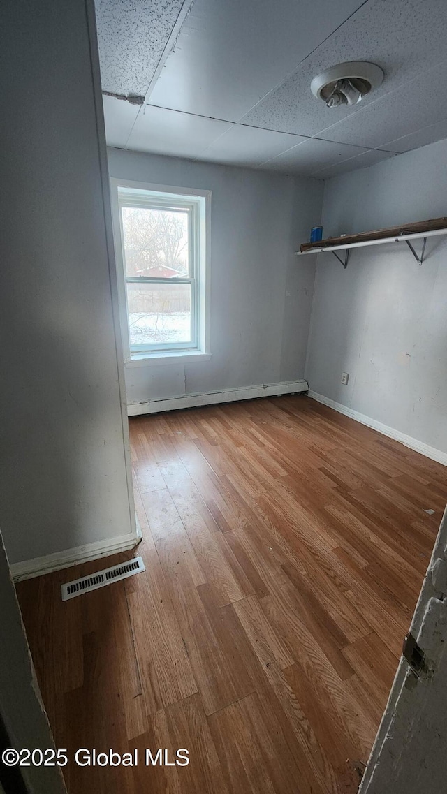 spare room with a paneled ceiling and hardwood / wood-style floors