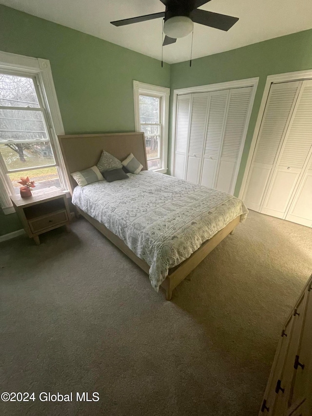 unfurnished bedroom with carpet flooring, multiple windows, multiple closets, and ceiling fan