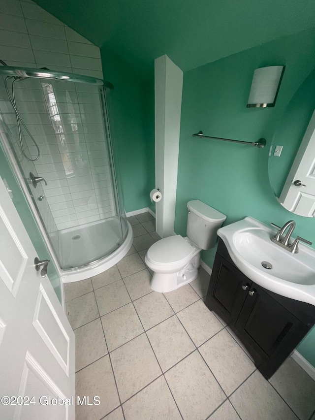 bathroom featuring tile patterned flooring, vanity, toilet, and a shower with door