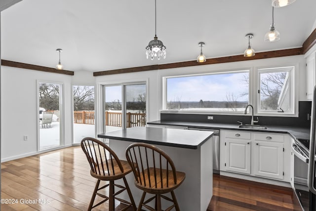 kitchen with sink, white cabinetry, hanging light fixtures, a kitchen breakfast bar, and a kitchen island