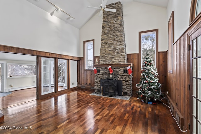 unfurnished living room with hardwood / wood-style floors, high vaulted ceiling, wooden walls, a baseboard radiator, and ceiling fan