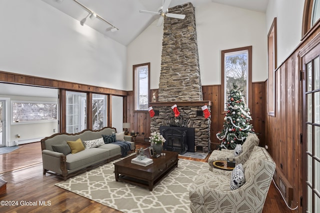 living room with wood walls, high vaulted ceiling, a baseboard radiator, ceiling fan, and hardwood / wood-style floors