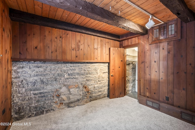 unfurnished room with wood ceiling, wood walls, carpet, and beamed ceiling