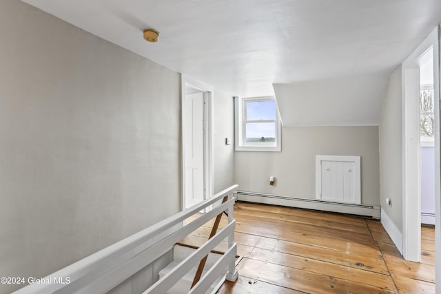 additional living space with lofted ceiling, a baseboard heating unit, and hardwood / wood-style floors