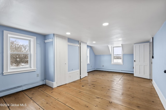 additional living space featuring lofted ceiling, baseboard heating, and light hardwood / wood-style flooring