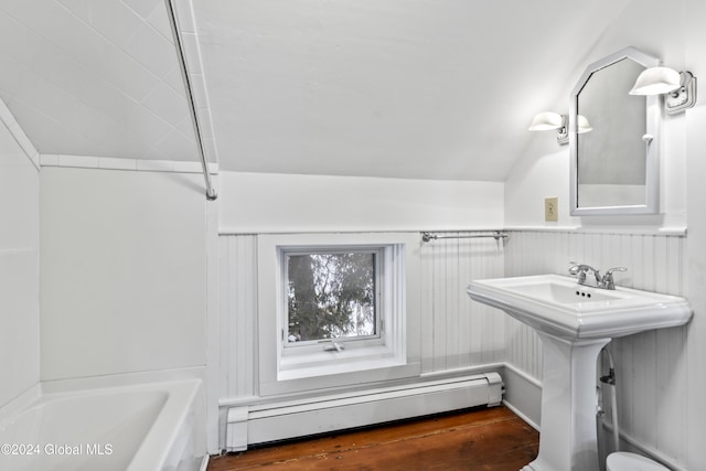 bathroom with sink, bathing tub / shower combination, a baseboard heating unit, wood-type flooring, and vaulted ceiling