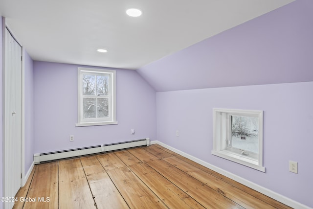 additional living space featuring wood-type flooring, lofted ceiling, and a baseboard heating unit