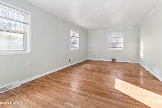 unfurnished room featuring a healthy amount of sunlight, crown molding, and light hardwood / wood-style flooring