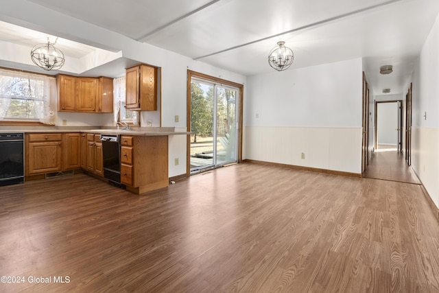 kitchen with an inviting chandelier, black dishwasher, kitchen peninsula, light hardwood / wood-style floors, and decorative light fixtures