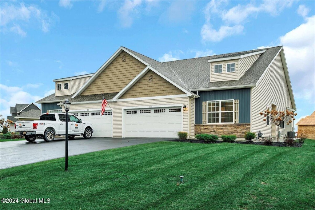 craftsman-style home with central AC unit, a garage, and a front lawn