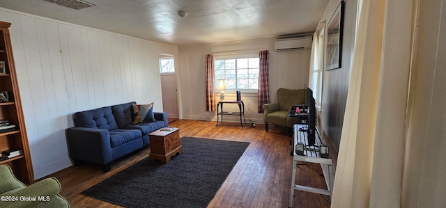 living room featuring wooden walls, dark hardwood / wood-style flooring, and a wall mounted air conditioner