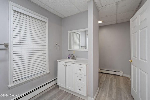 bathroom featuring vanity, hardwood / wood-style floors, a paneled ceiling, and a baseboard radiator