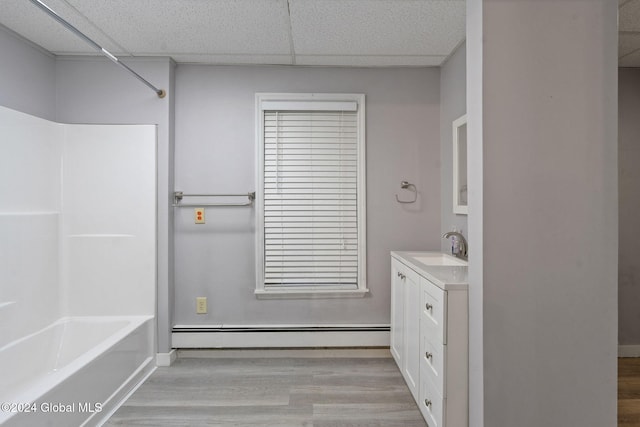 bathroom with shower / bath combination, a drop ceiling, vanity, baseboard heating, and hardwood / wood-style floors