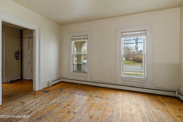 unfurnished room with light wood-type flooring and a baseboard heating unit