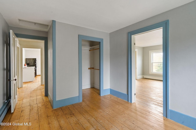 unfurnished bedroom with light hardwood / wood-style floors, baseboard heating, and a closet