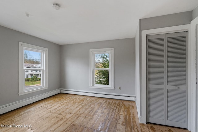 unfurnished bedroom featuring a closet, light hardwood / wood-style flooring, and a baseboard heating unit