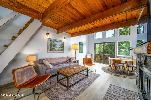 living room with a fireplace, beam ceiling, light wood-type flooring, and wood ceiling