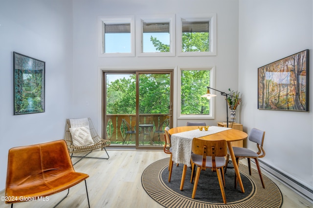 dining room featuring a towering ceiling and light hardwood / wood-style flooring