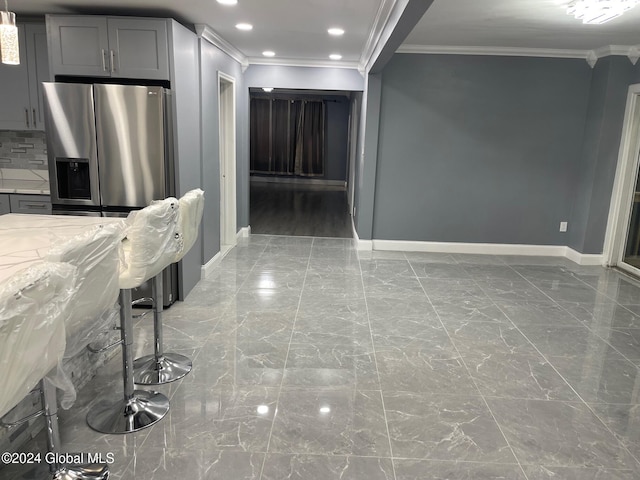 kitchen featuring stainless steel fridge with ice dispenser, gray cabinets, light stone counters, and crown molding