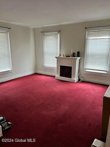 unfurnished living room with carpet floors and ornamental molding