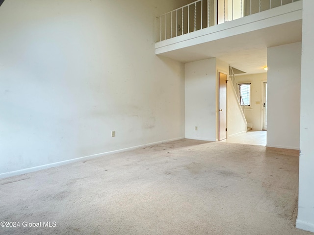 carpeted empty room featuring a towering ceiling