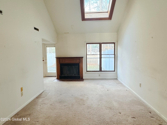 unfurnished living room with light carpet, a skylight, and high vaulted ceiling