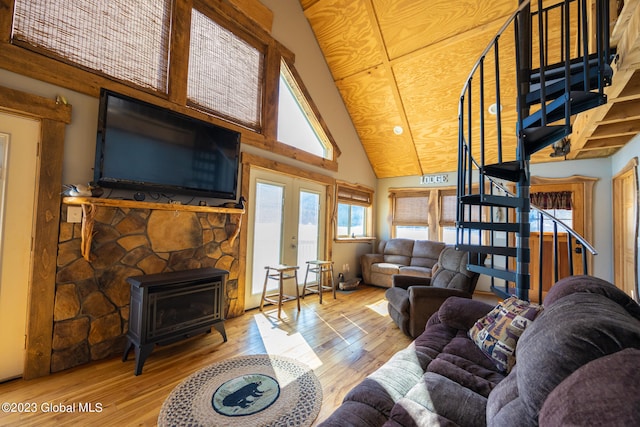 living room with a wood stove, french doors, high vaulted ceiling, and light hardwood / wood-style floors