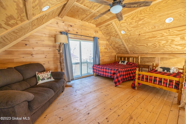 bedroom featuring access to exterior, ceiling fan, wooden walls, and wood-type flooring