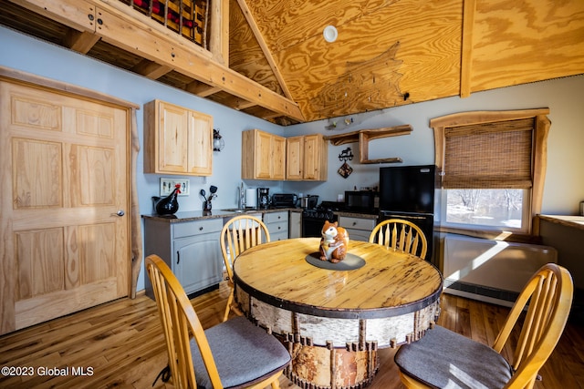 dining space with sink, lofted ceiling, and hardwood / wood-style flooring