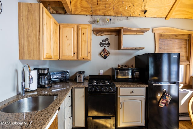 kitchen with light brown cabinetry, sink, black appliances, dark stone countertops, and hardwood / wood-style floors