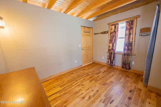 spare room with beamed ceiling, light wood-type flooring, and wooden ceiling