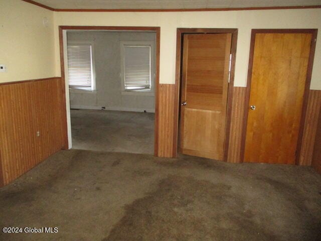 hall featuring carpet, crown molding, and wooden walls