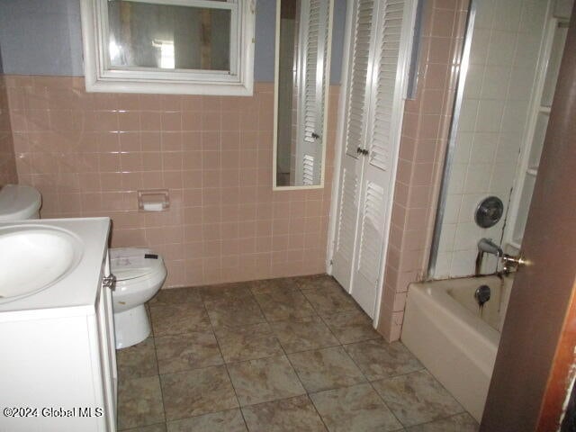 full bathroom featuring shower / bathtub combination, vanity, toilet, and tile walls