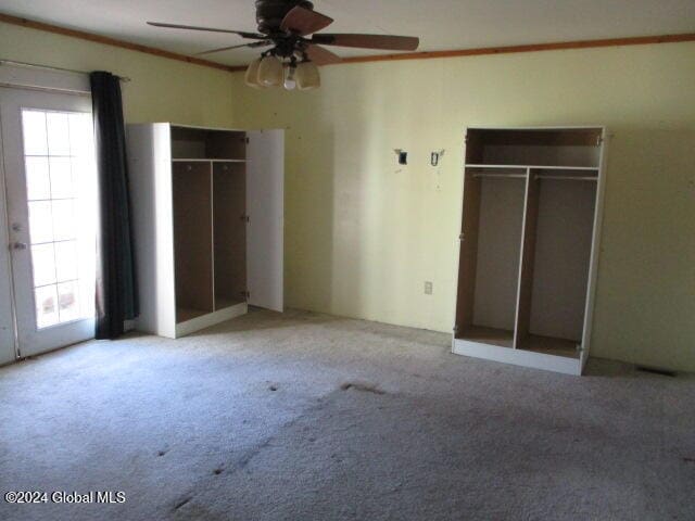 unfurnished bedroom with french doors, two closets, ceiling fan, and light colored carpet