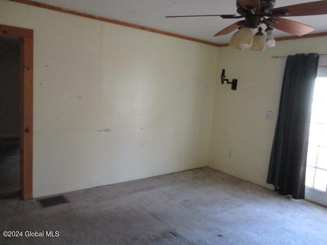 carpeted empty room with ceiling fan and crown molding