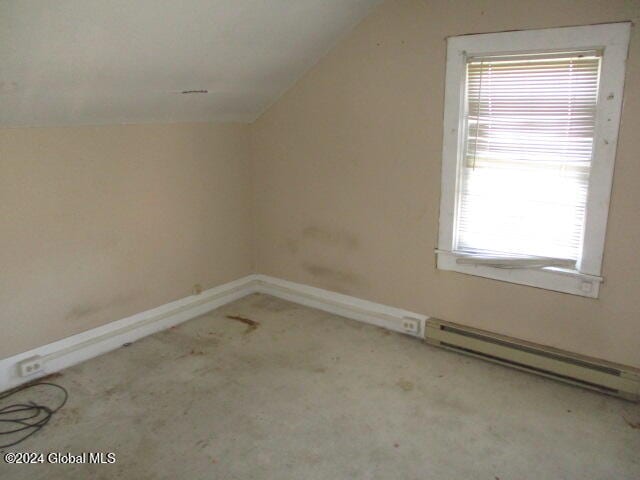 additional living space featuring light carpet, a baseboard heating unit, and lofted ceiling