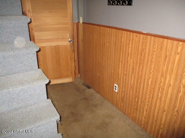 staircase with carpet flooring and wood walls