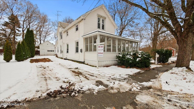 view of front of home featuring a sunroom, a garage, and an outdoor structure