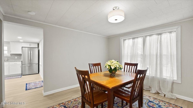 dining area with crown molding and light hardwood / wood-style flooring