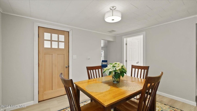 dining room with light wood-type flooring and ornamental molding