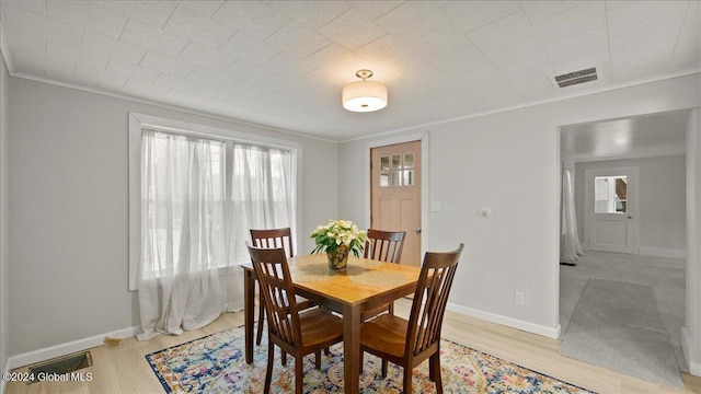 dining space featuring light hardwood / wood-style flooring and crown molding